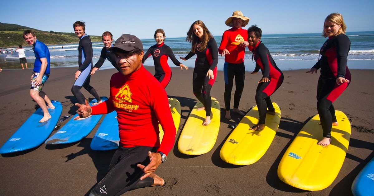 Jóvenes aprendiendo a hacer surf con su monitor 